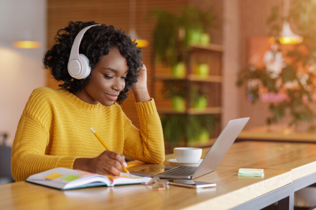 Woman listens to an audio recording as she takes notes