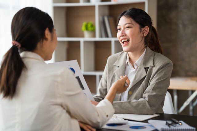 A woman converses comfortably with a workmate.