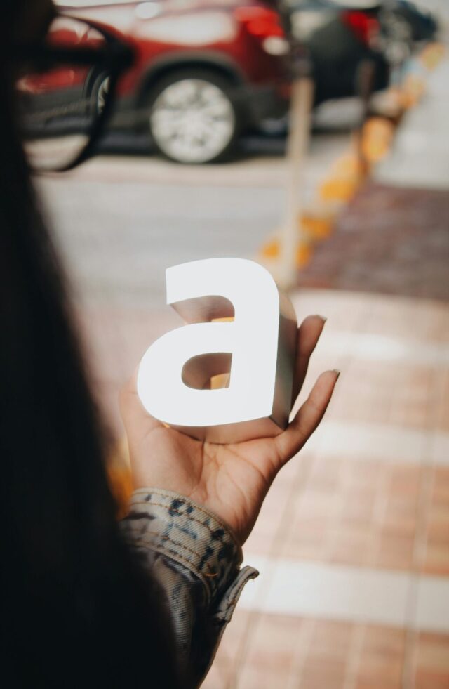 A woman holds the vowel A in her hand