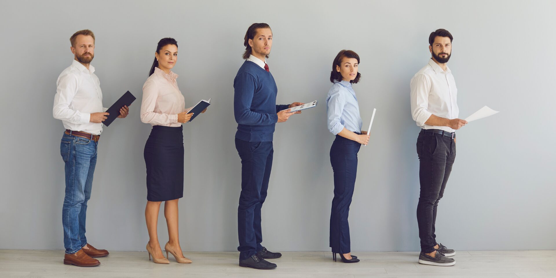 Job applicants stand in line waiting for an interview with their CVs in-hand