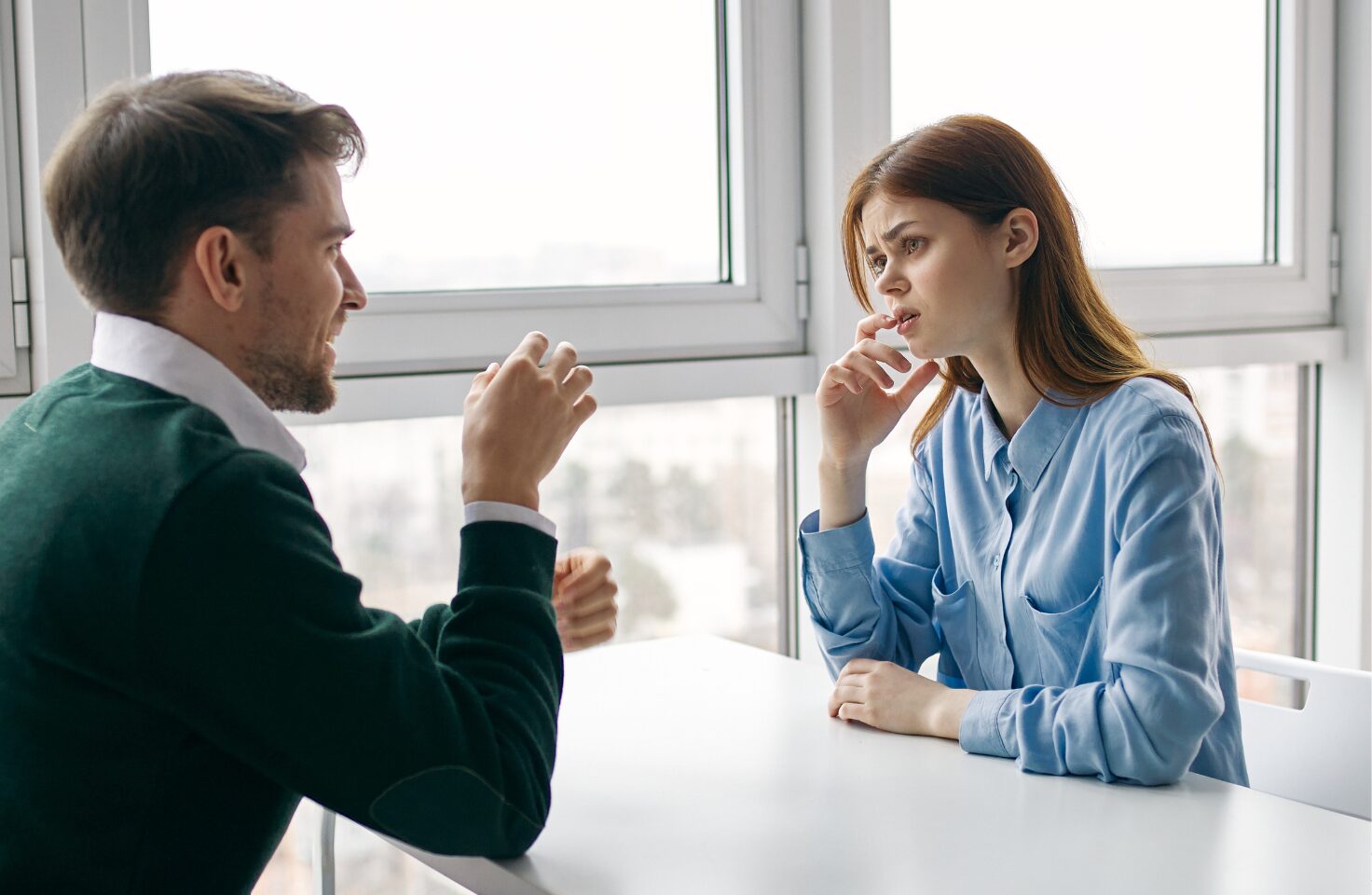 A man is speaking to a woman who is visibly confused as she tries to understand him.