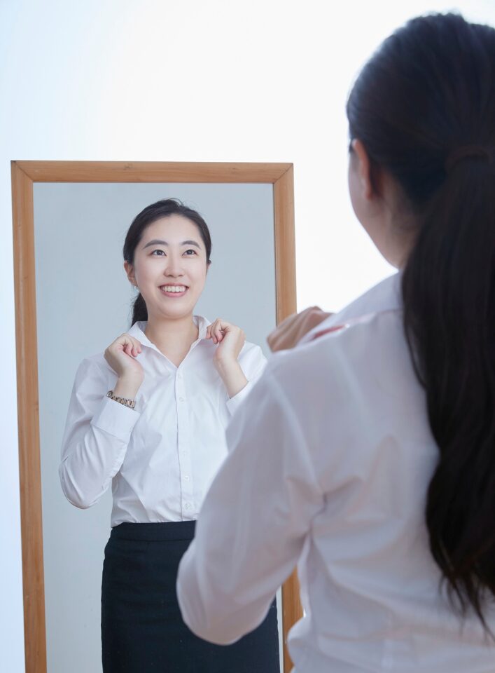 A woman looks confidently into the mirror.