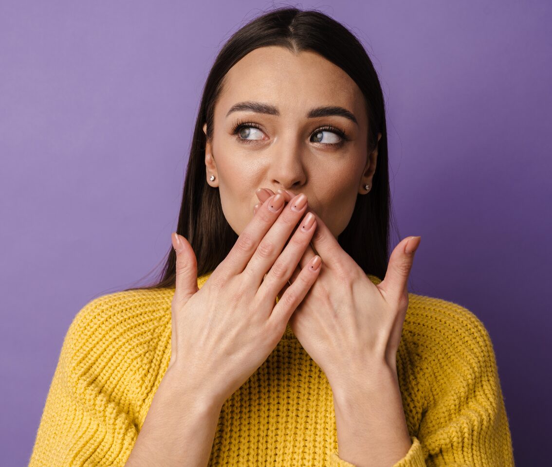A young woman covers her mouth, unsure of how to pronounce R.