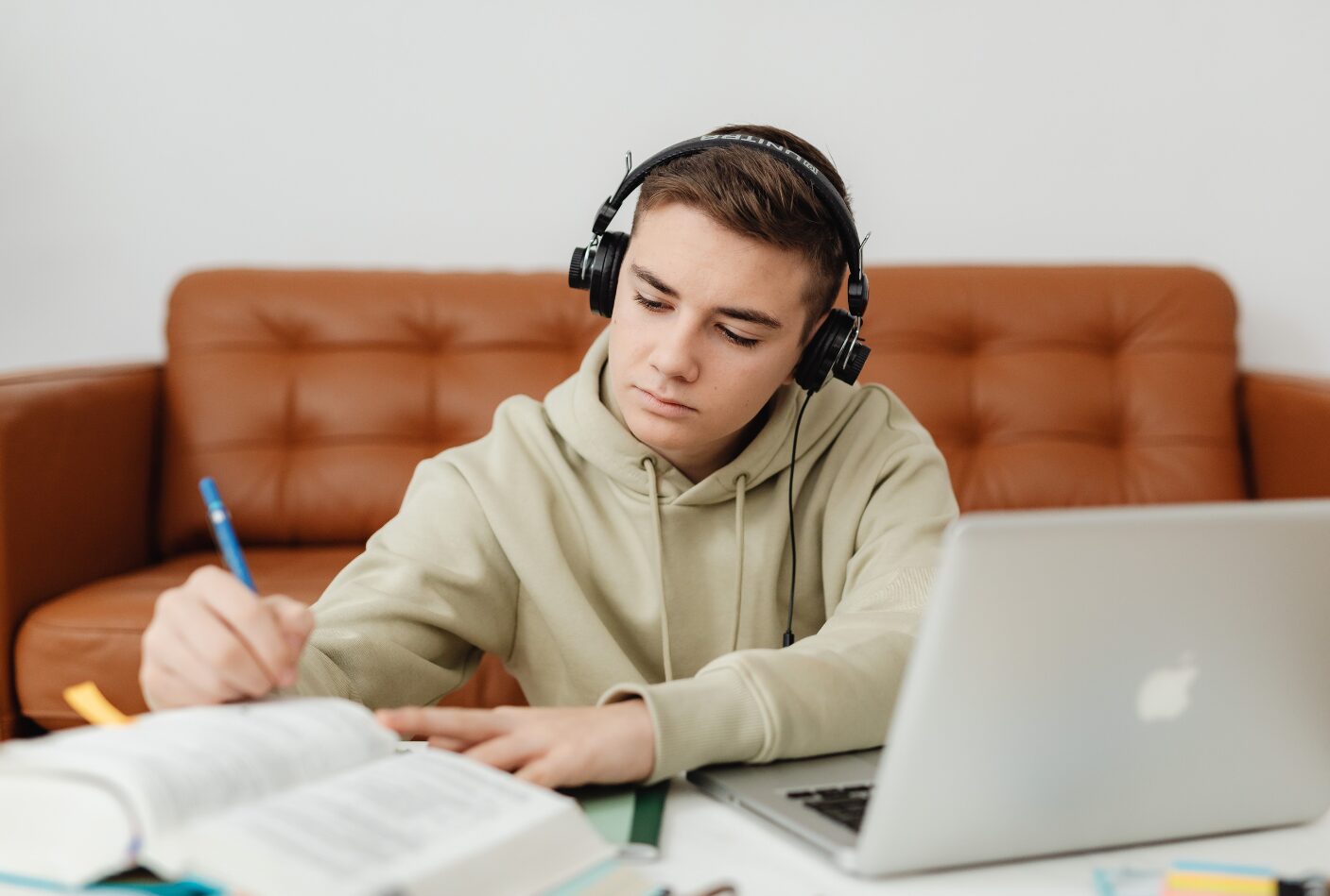 A student takes notes as he listens to an audio.